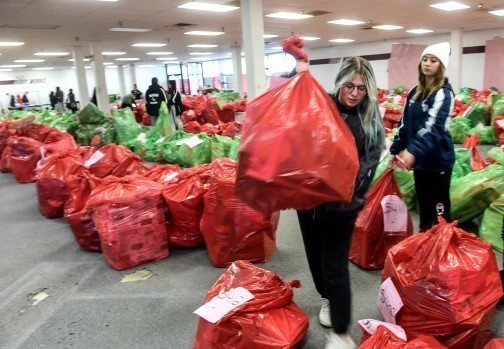 Cassidy Hathaway, left, and Chloe Kissling, both 17 and both seniors at Conrad Weiser High School, take bags of toys to awaiting recipients at the Salvation Army of Reading’s toy distribution at its facility at 5370 Allentown Pike, Temple, on Friday